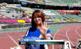 a woman in a blue shirt stands on a track in front of a podium with the number 3 on it