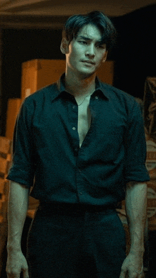 a man in a black shirt is standing in a dark room .