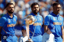 a group of cricket players standing next to a trophy .