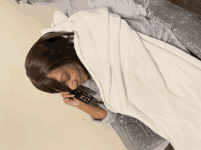 a woman wrapped in a white blanket is talking on a cellphone