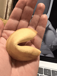 a person is holding a fortune cookie in front of a keyboard