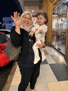 a woman holding a baby with a fendi purse behind her