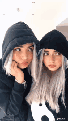 two girls wearing black hoodies with tiktok written on the bottom right