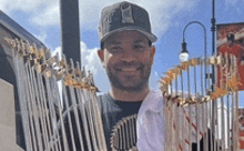 a man in a baseball cap is holding a trophy in front of a fence .