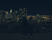 two people standing on a balcony looking at a city skyline at night