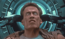 arnold schwarzenegger is sitting in a chair with his arms around his head and looking up .