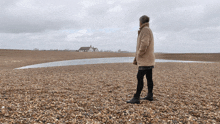 a woman standing on a beach looking at a house