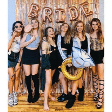 a group of women are posing for a picture in front of a bride 's backdrop .