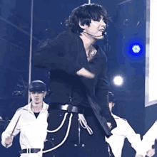 a man in a black shirt and black pants is dancing on a stage