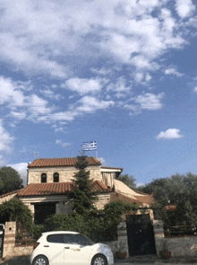 a white car is parked in front of a house with a flag on top of it