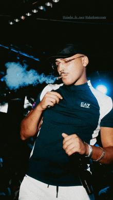 a man wearing a blue ea7 shirt smoking a cigar