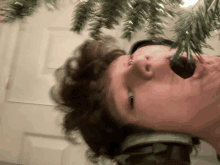 a young man with headphones on looks up at a christmas tree