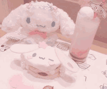 a stuffed animal is sitting on a table next to a sandwich and a glass of pink liquid .