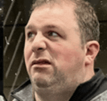 a close up of a man 's face with a beard and a serious look on his face .