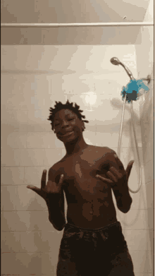 a shirtless man in a shower with a blue sponge on his head