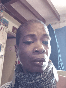 a woman wearing a scarf and earrings has a no smoking sign on the wall behind her