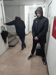 a man in a black jacket stands in a hallway