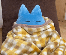 a blue stuffed animal is wrapped in a blanket