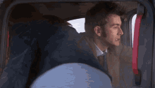 a man sitting in a car with a red handle on the door