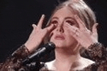 a woman is covering her face with her hands while standing in front of a microphone .