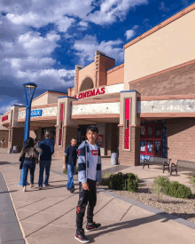 a boy wearing a levis shirt stands in front of a cinema