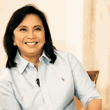 a woman in a light blue polo shirt smiles for the camera