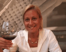 a woman is holding a glass of wine and smiling