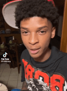 a young man wearing a hat and a black shirt with red letters that says tik tok