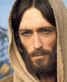 a close up of a man with a beard wearing a hooded robe