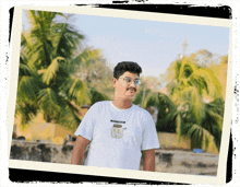 a man wearing a white t-shirt with a jar on it stands in front of palm trees