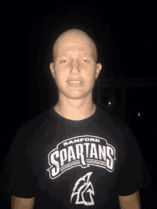 a man with a spartans t-shirt on stands in the dark