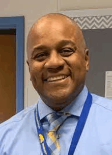 a man wearing a blue shirt and tie is smiling .