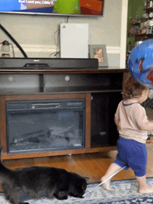 a little girl standing in front of a fireplace holding a balloon