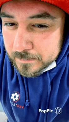 a man with a beard wearing a blue hoodie that says poppic on it