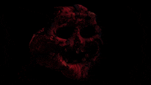 a black background with a red object in the foreground that looks like a skull