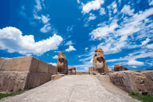 a blue sky with white clouds is behind a stone statue