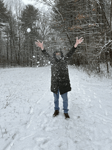 a person throwing snowballs in the air in a snowy field