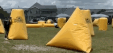 a group of people are playing a game of paintball in a field with a house in the background .