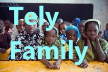 a group of children are sitting at a table in a classroom with the words tely family .