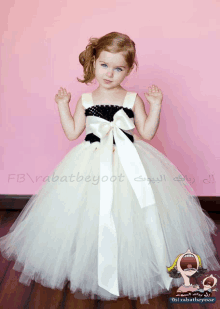 a little girl is wearing a white and black dress with a white ribbon