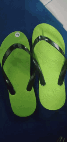 a pair of green flip flops with black straps and the number 41 on the side