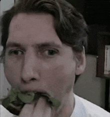 a man is eating a piece of lettuce with his hands