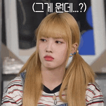 a girl with blonde hair and pigtails is making a funny face with korean writing above her