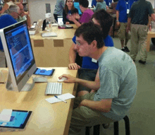 a man wearing a shirt that says ' sydney ' on it sits at a computer