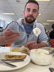 a man wearing a hoodie that says ice surfer is eating food