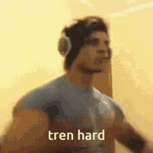 a man wearing headphones and a blue shirt with the words tren hard written on the bottom