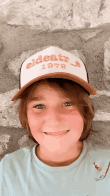 a young boy wearing a trucker hat that says eldest 1979