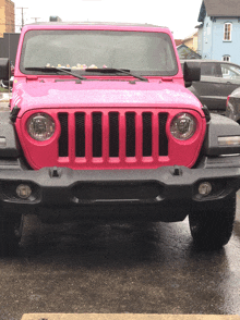 a pink jeep is parked in the rain