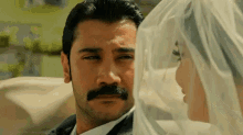 a man with a mustache looks at a woman in a wedding dress