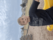 a boy wearing a black under armour shirt stands on a yellow slide